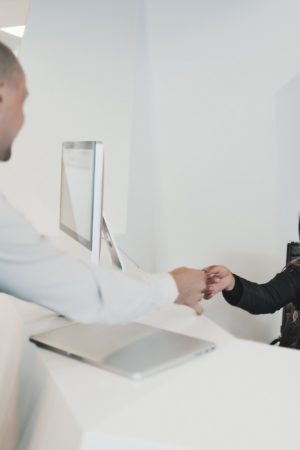 A man shaking hands with a woman behind her desk.
