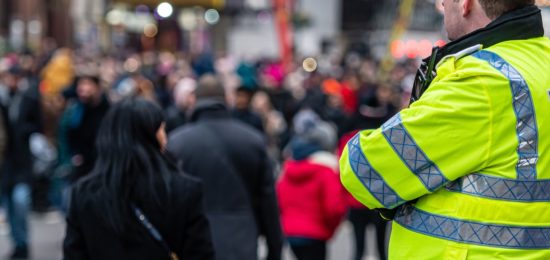 A man in a high-vis jacket looking onward to a crowded street.